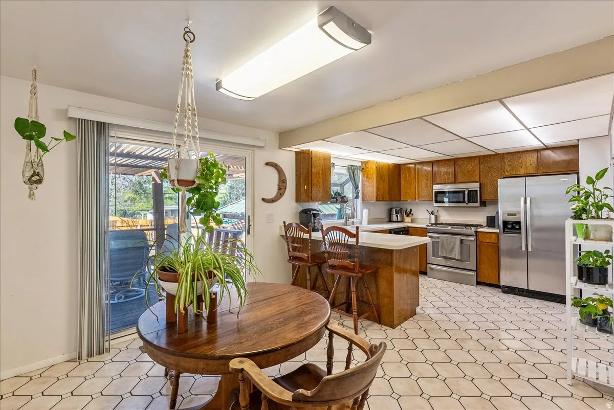 Kitchen featuring wood cabinetry, stainless steel appliances, and a central island with bar seating