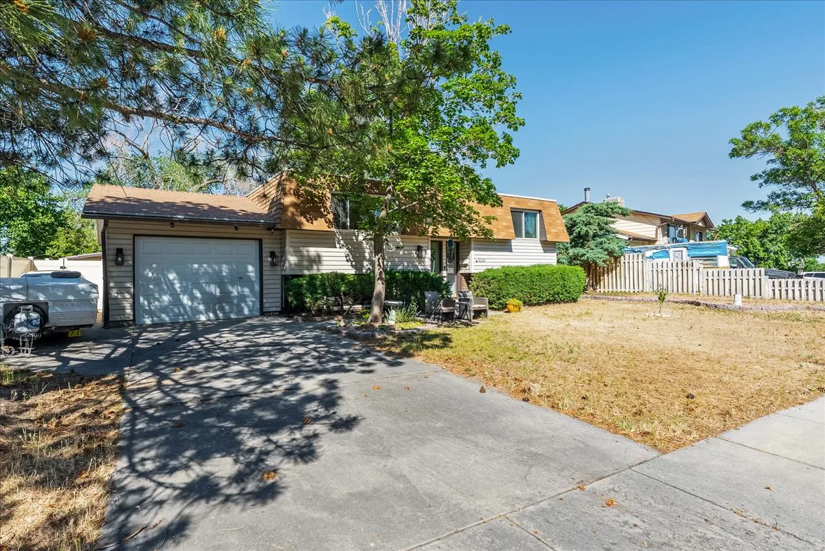 Property exterior featuring a single-car garage, asphalt driveway, and mature landscaping