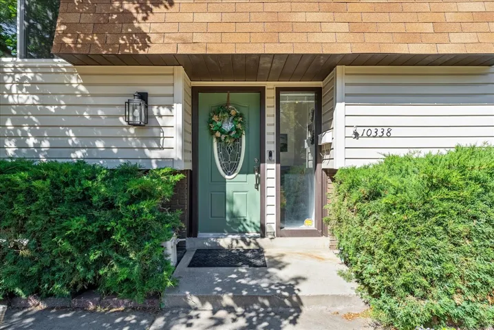Entryway featuring a green door with oval glass insert, vertical sidelight, and a matte black wall lantern