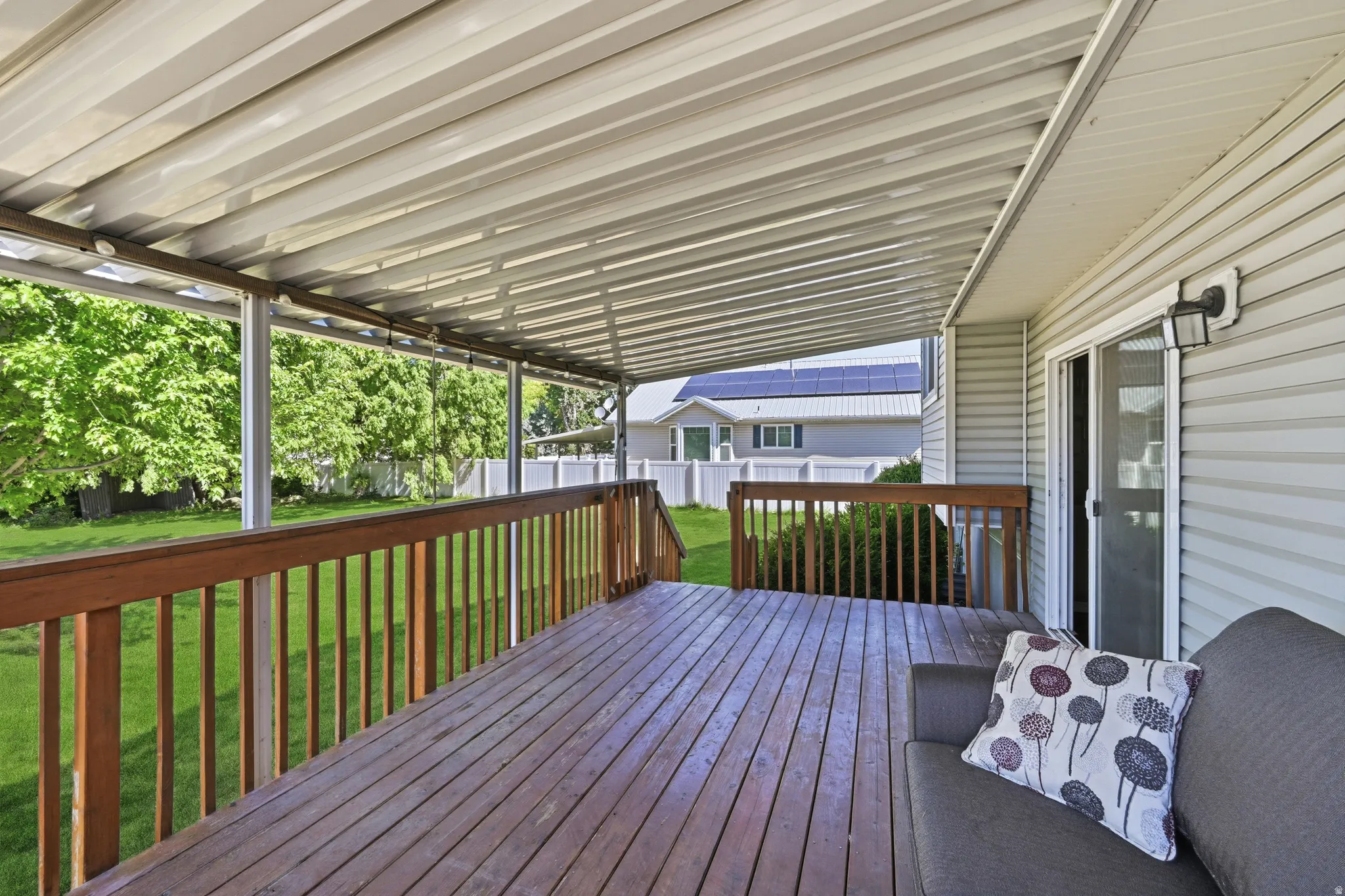 Spacious outdoor deck featuring wood-finish flooring, wood railings, and a protective overhead cover