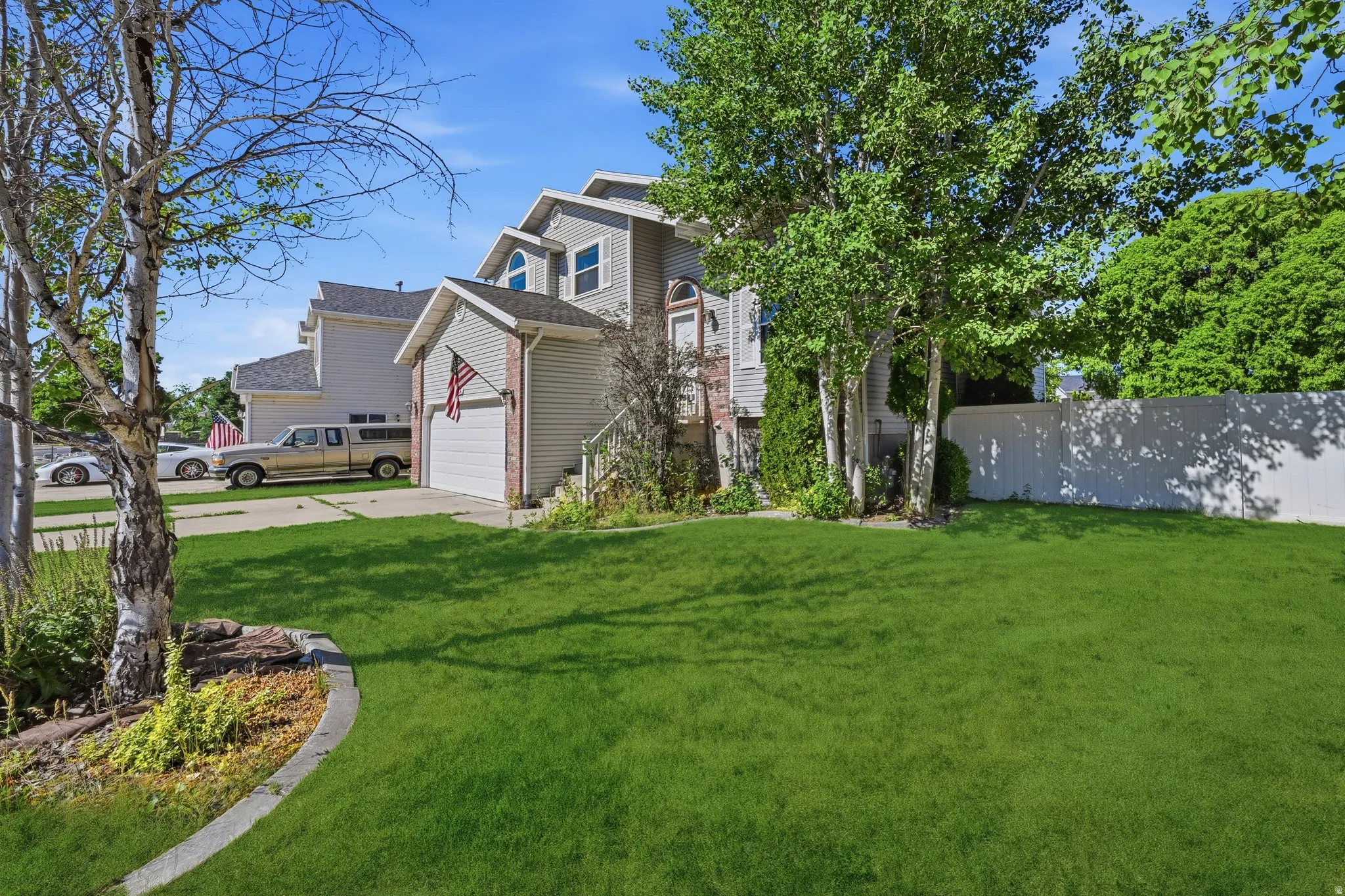 Front yard featuring a manicured lawn, established landscaping, and mature trees
