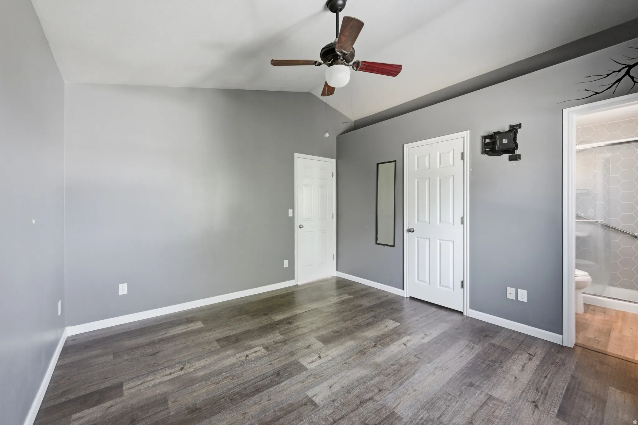 Interior room featuring wood-finish flooring, vaulted ceiling, and a ceiling fan with light fixture