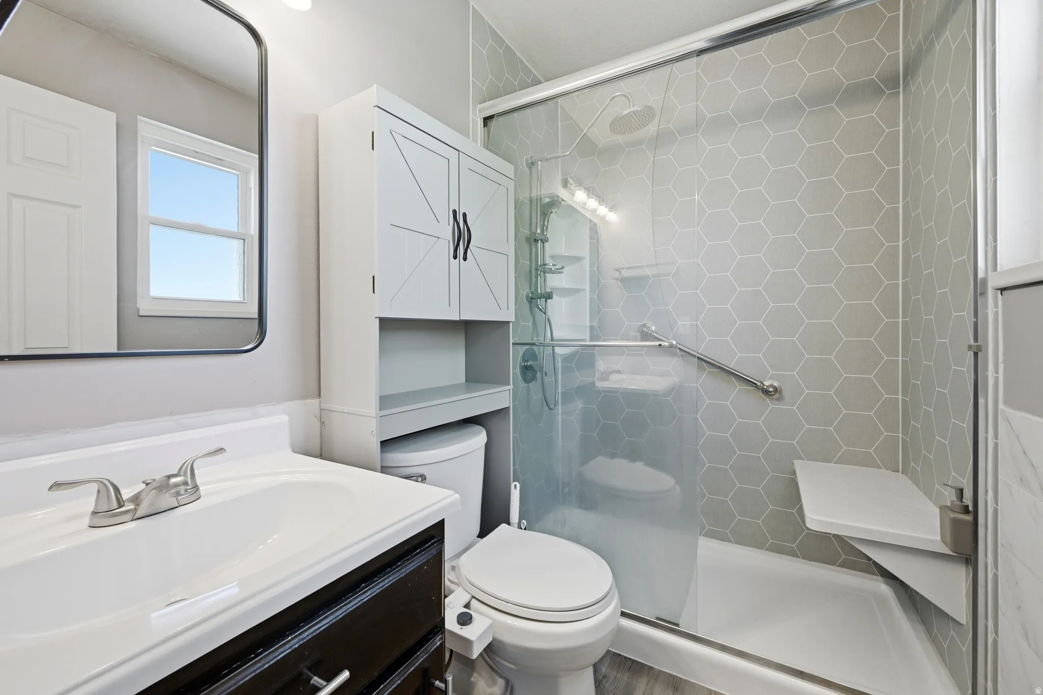 Bathroom featuring a hexagon-tiled shower with a built-in bench, glass enclosure, and grab bar
