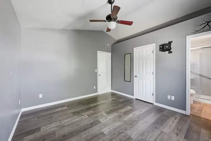 Interior room featuring wood-finish flooring, vaulted ceiling, and a ceiling fan with light fixture