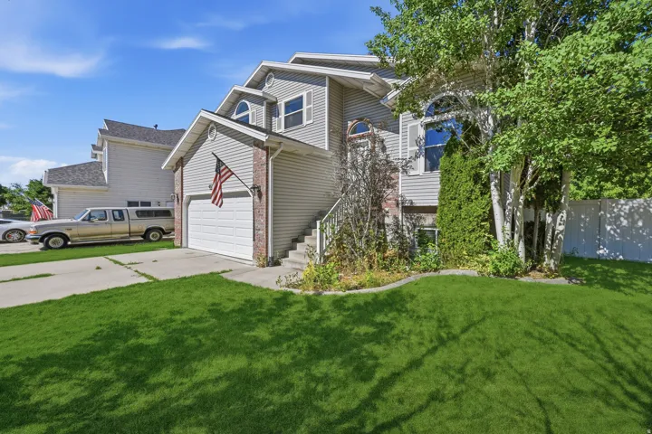 Two-story residence featuring light gray siding with brick accents, an integrated single-car garage, and a concrete driveway