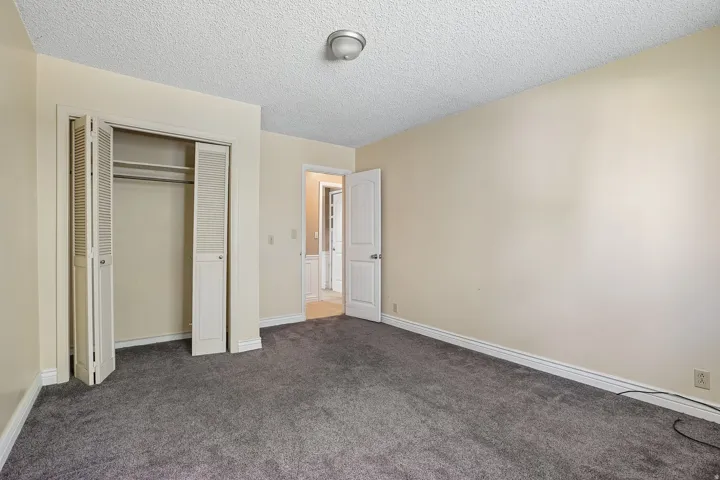 Spacious room featuring gray carpet flooring, light cream wall paint, and white baseboards