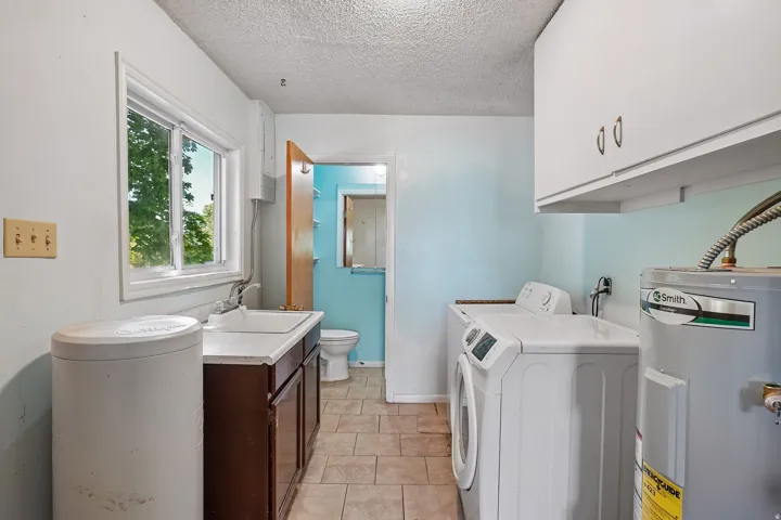 Utility room featuring a window, built-in sink with cabinetry, and tiled flooring