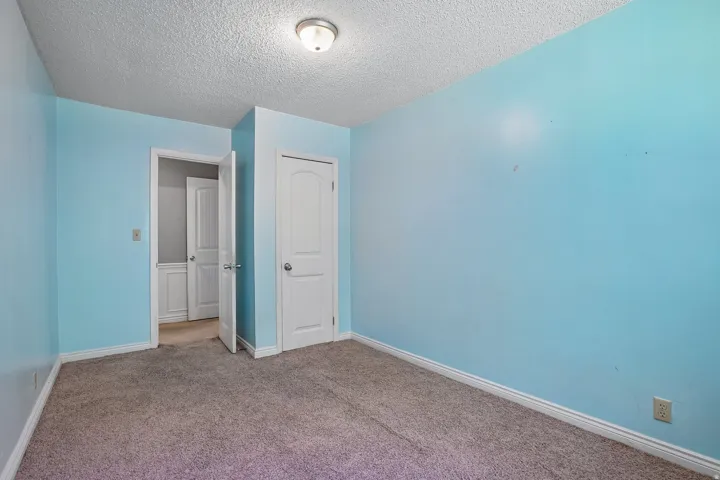 Room featuring light blue walls, gray carpet, white trim, a flush mount ceiling light, and a white interior door