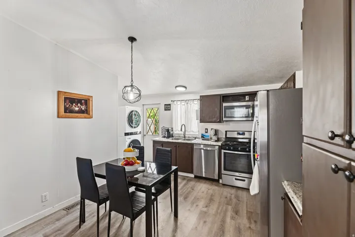Open-concept kitchen and dining area featuring wood-finish flooring, dark wood cabinetry, and stainless steel appliances