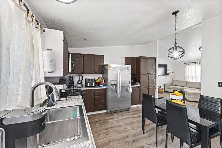 Kitchen featuring wood-finish cabinetry, stainless steel sink with gooseneck faucet, light-toned countertops, and wood-finish flooring