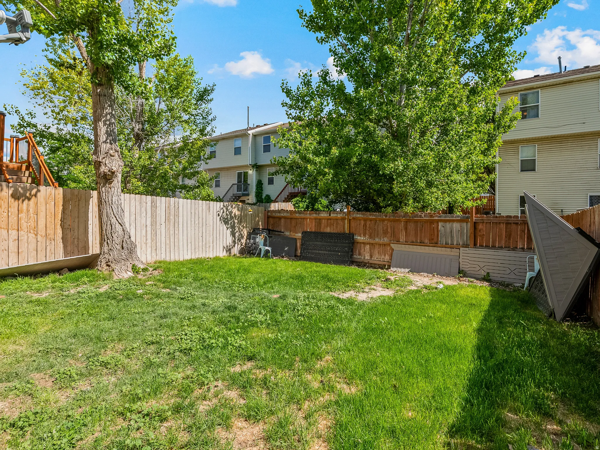 Expansive backyard space featuring a mature tree, a wooden privacy fence, and grass coverage