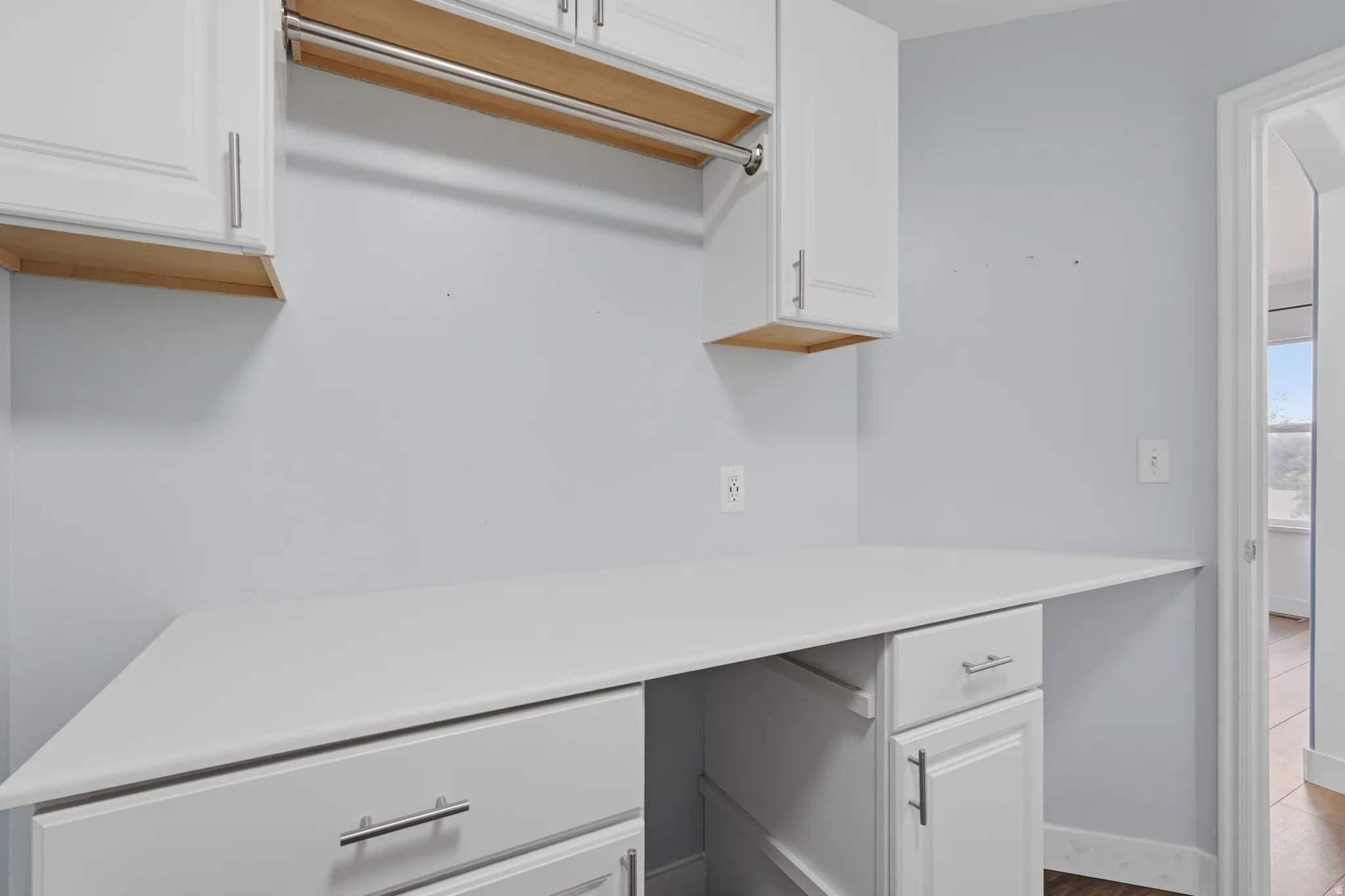 Dedicated utility space featuring white cabinetry, a built-in hanging rod, a generous countertop, and under-counter storage