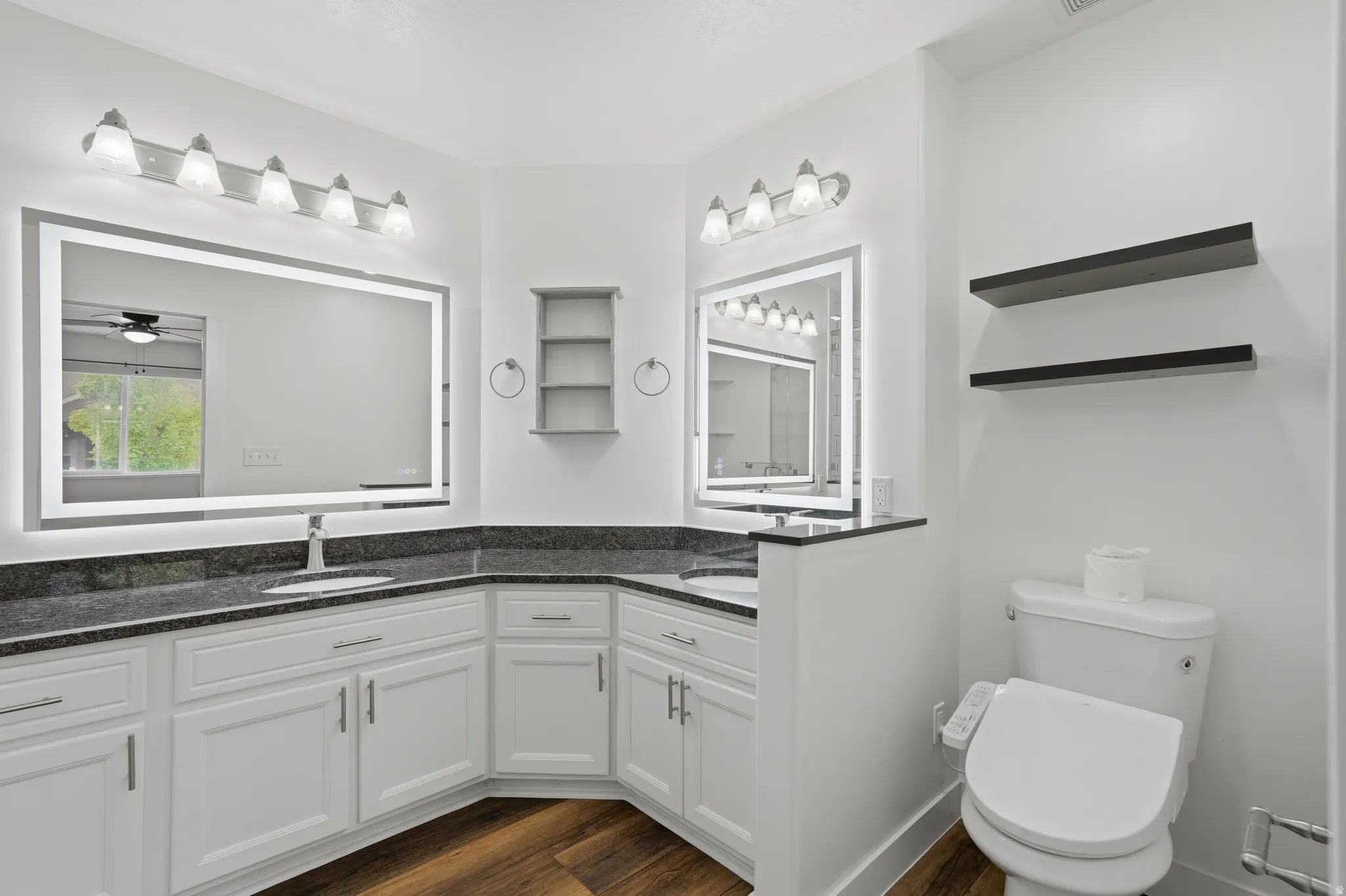 Dual white vanity cabinets with dark countertops and integrated sinks