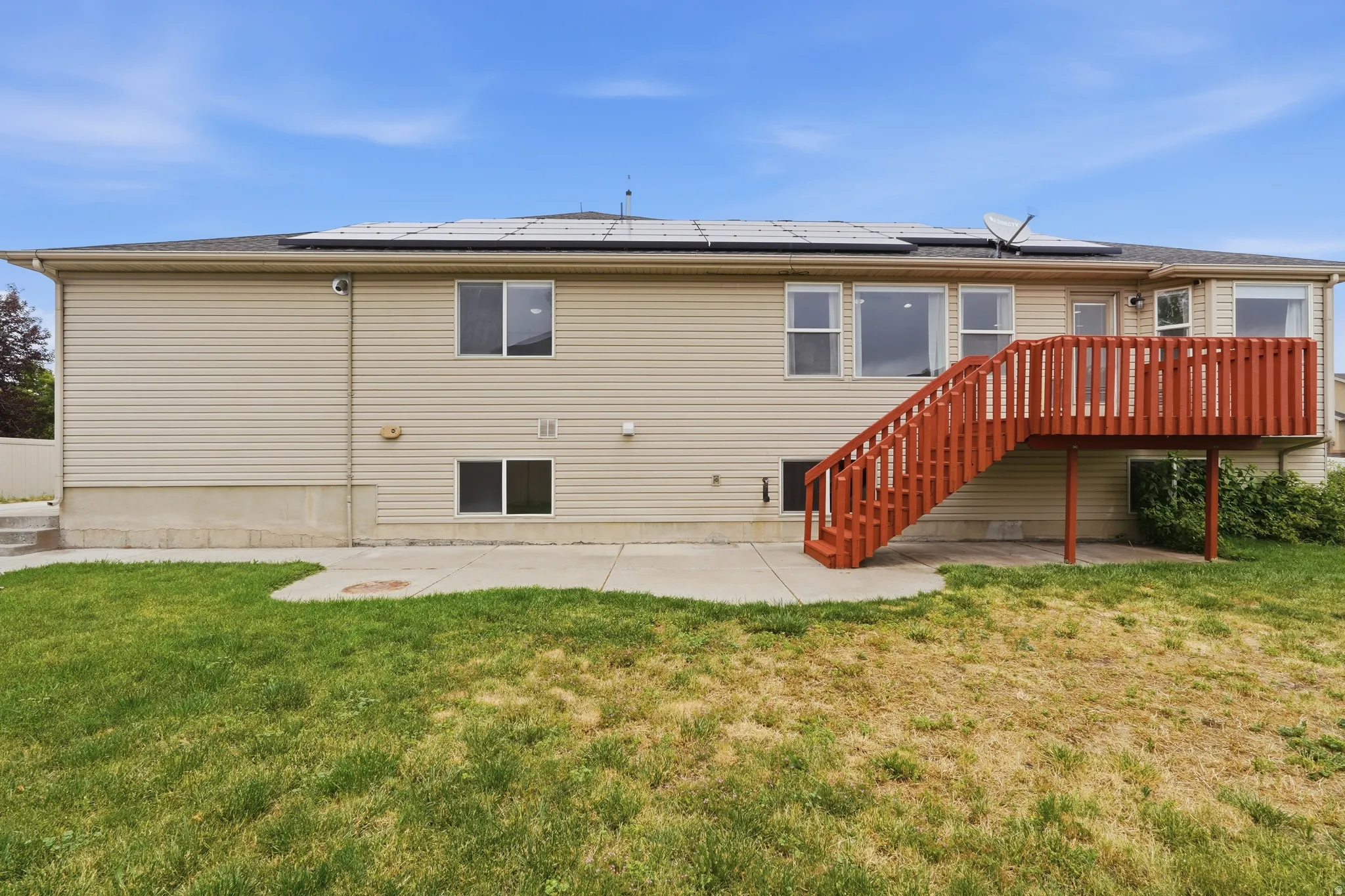 Rear exterior with beige siding and a red-stained wooden deck