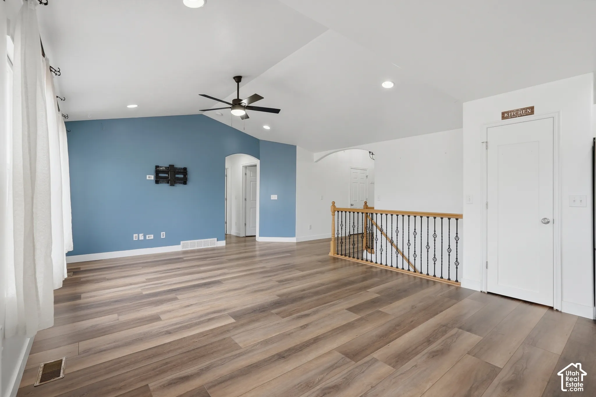 Spacious living area featuring wood-finish flooring, a vaulted ceiling, recessed lighting, and a modern ceiling fan