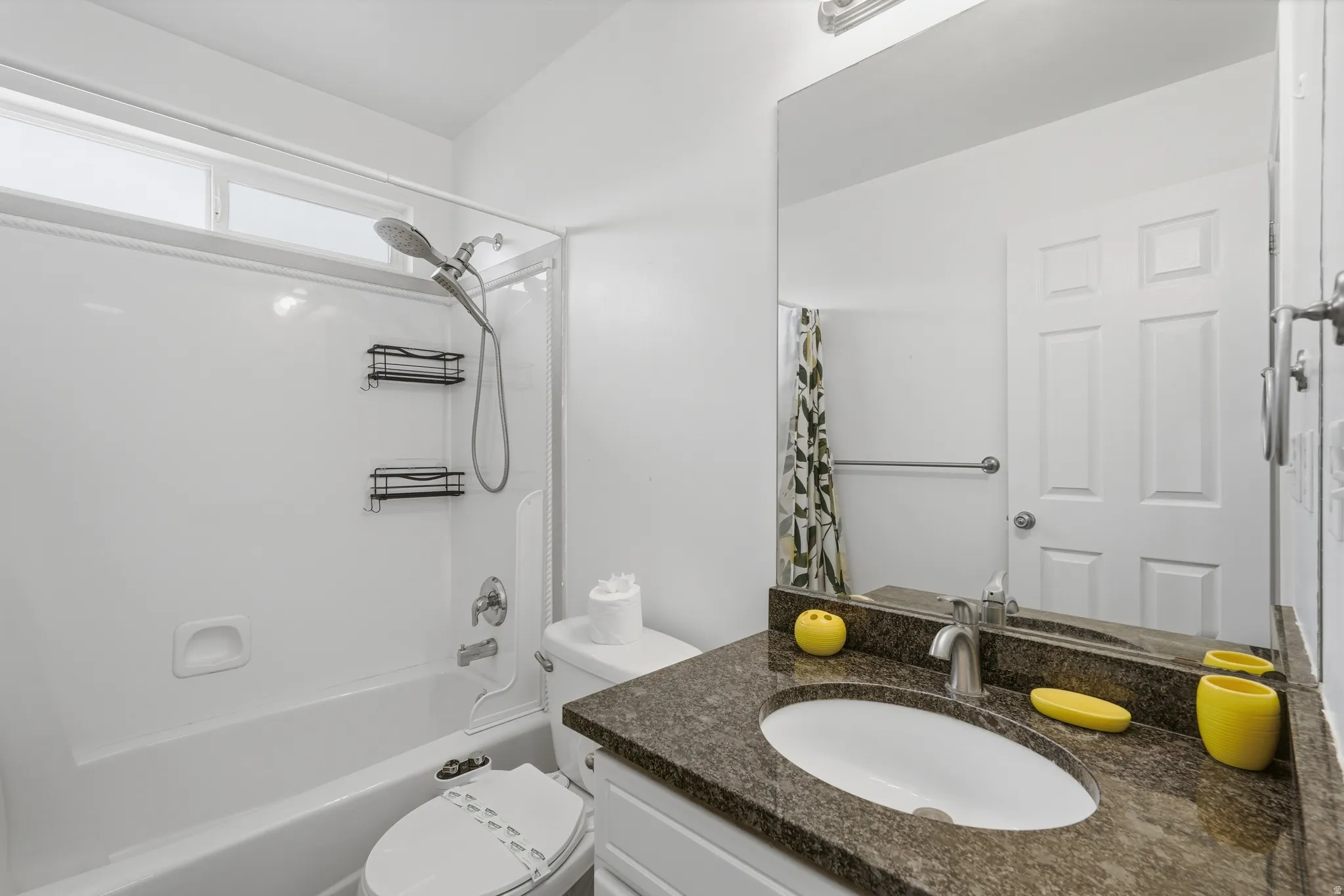 Bathroom featuring a shower-over-tub combination with a handheld showerhead, a high-set window, and a white vanity with a dark speckled countertop and undermount sink