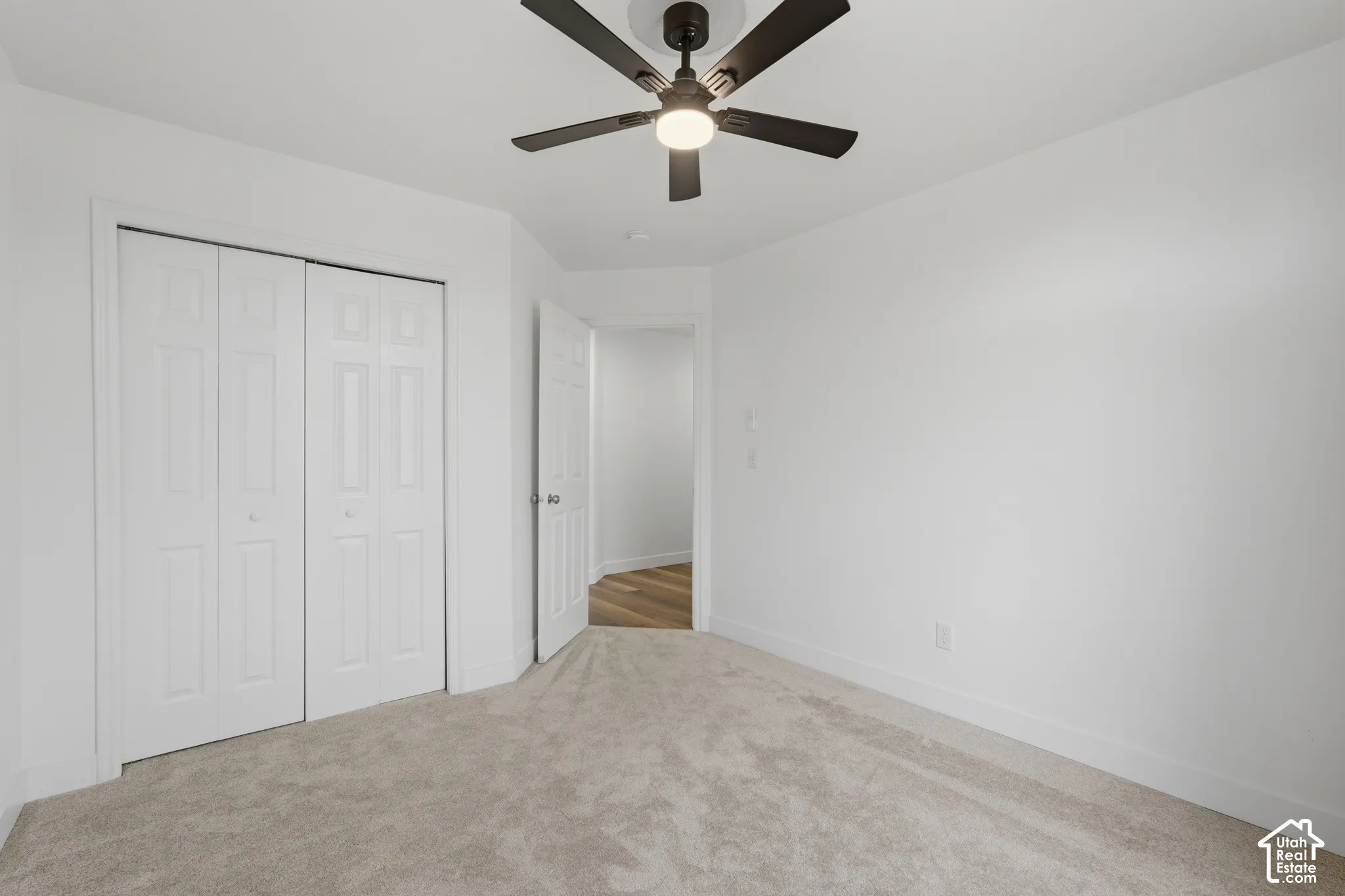 Carpeted room with white walls, bi-fold closet doors, a ceiling fan with integrated lighting, and white baseboards