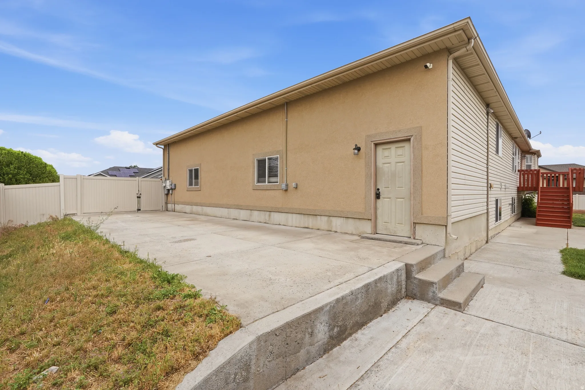 Exterior featuring a stucco and siding finish, concrete patio, and a privacy fence