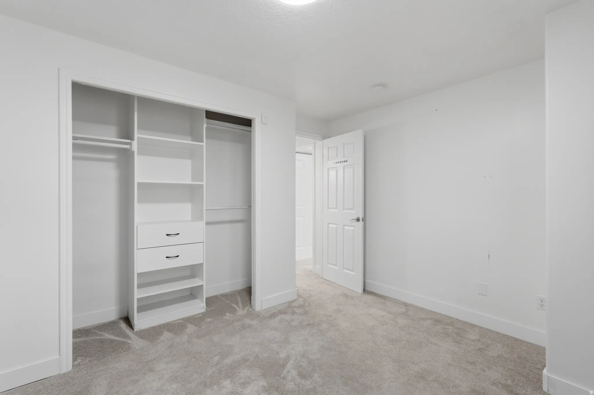 Bright interior space featuring a built-in closet system with shelving, drawers, and hanging rods