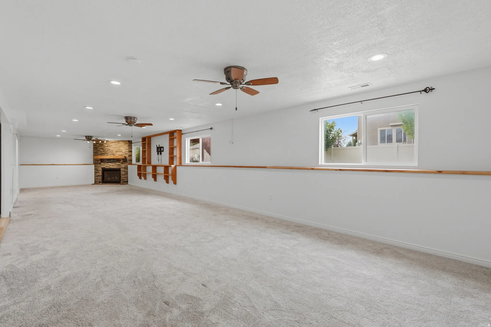 Spacious room featuring light-colored carpeting, multiple ceiling fans, and recessed lighting