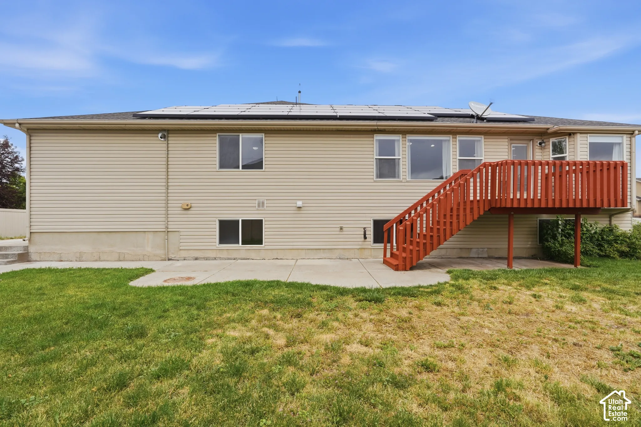 Rear exterior with beige siding and a red-stained wooden deck