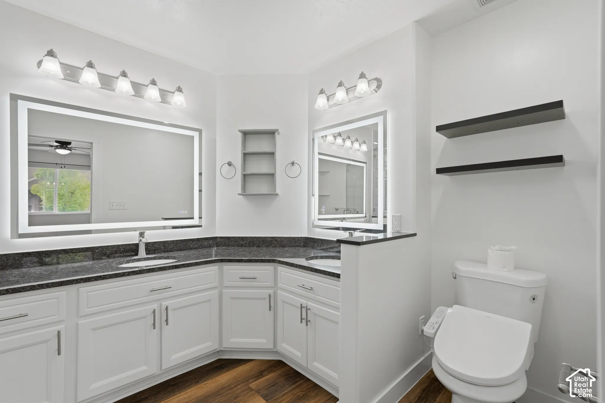 Dual white vanity cabinets with dark countertops and integrated sinks