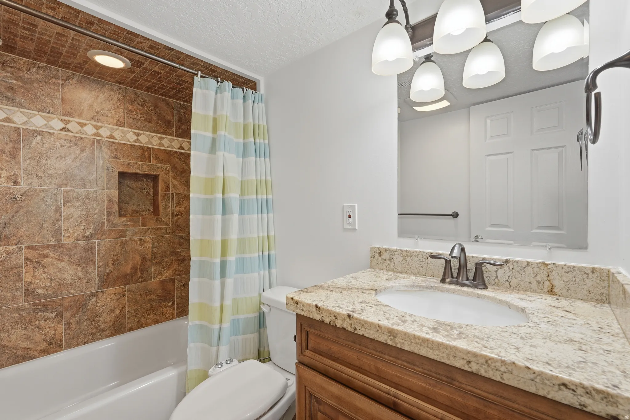 Full bathroom featuring a tub-shower combination with brown tile surround and an integrated niche