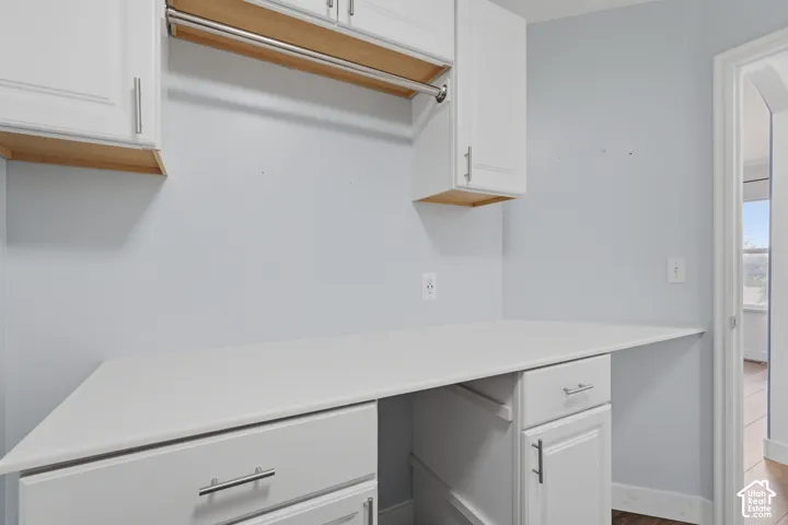 Dedicated utility space featuring white cabinetry, a built-in hanging rod, a generous countertop, and under-counter storage