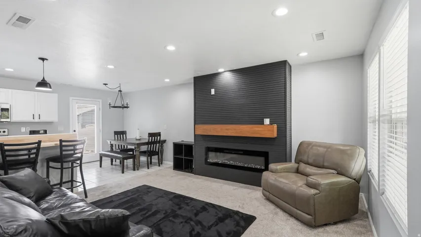 Living area featuring an electric fireplace with a wood mantle, shiplap accent wall, and recessed lighting