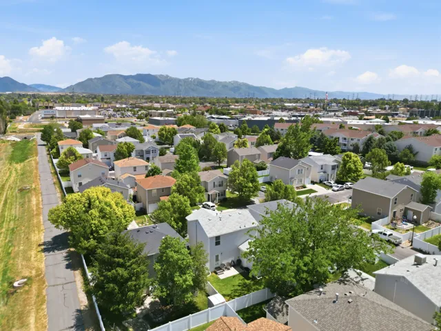 Aerial perspective showcasing a residential area with varied housing styles, mature trees, and individual fenced yards