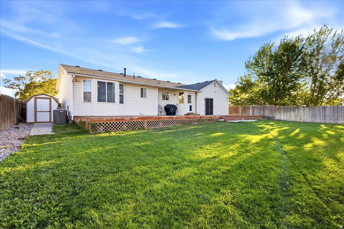 Expansive backyard featuring a large wooden deck, white siding, and a storage shed