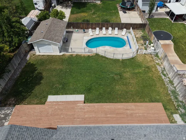 Private backyard featuring an in-ground swimming pool, a dedicated pool deck, a detached garage with an overhead door, and a spacious wood-finish deck