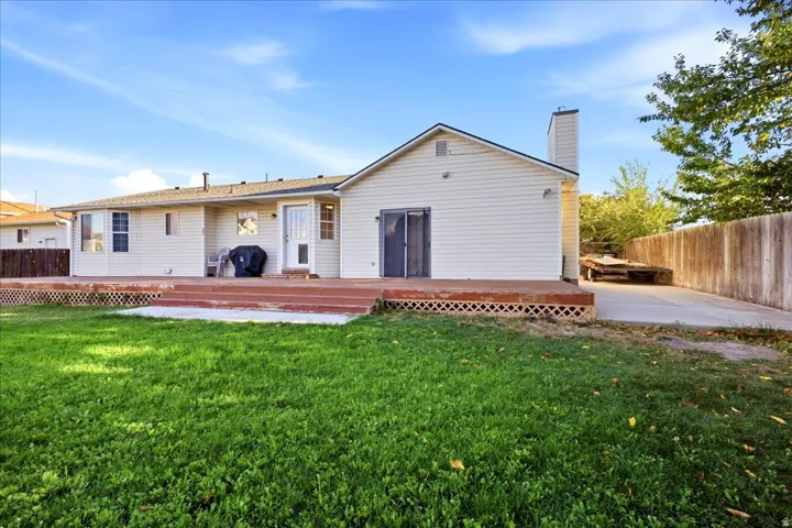 Expansive lawn with a multi-level wood deck, white vinyl siding, and a privacy fence