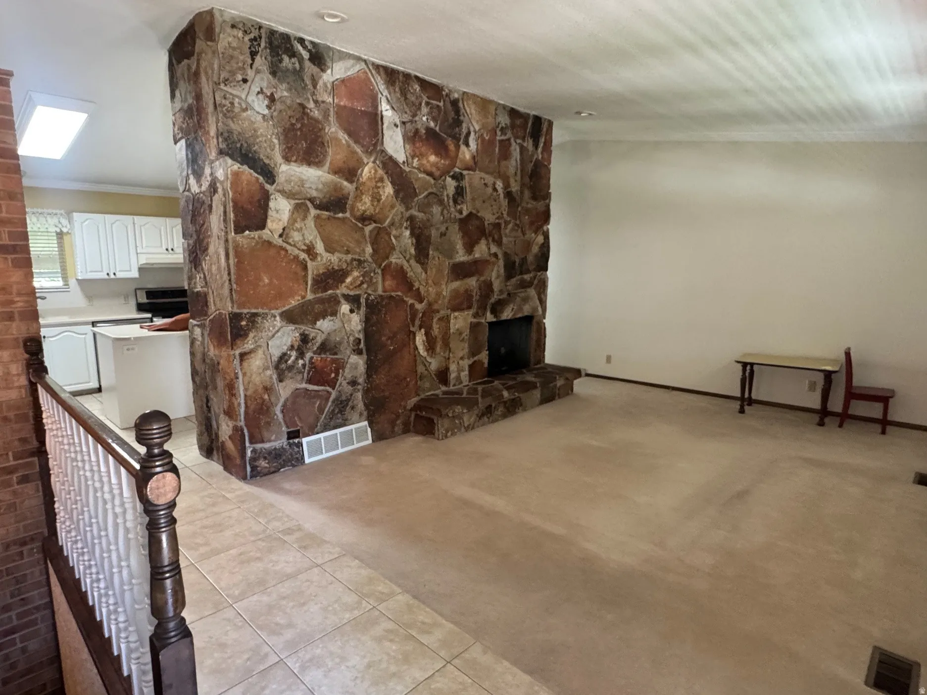 Floor-to-ceiling stone fireplace feature with hearth, complemented by light-toned wall-to-wall carpeting
