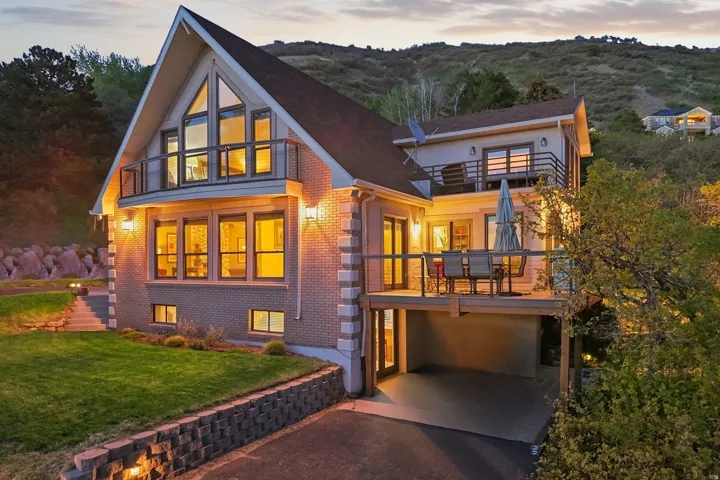 Modern architectural design featuring a brick and siding exterior, a prominent gable roofline, and multiple balconies with metal railings