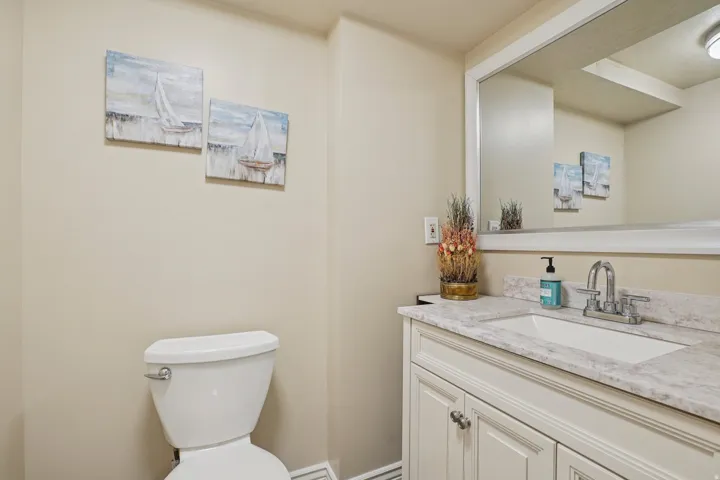 Bathroom featuring a white vanity with paneling, a rectangular undermount sink, and a speckled countertop