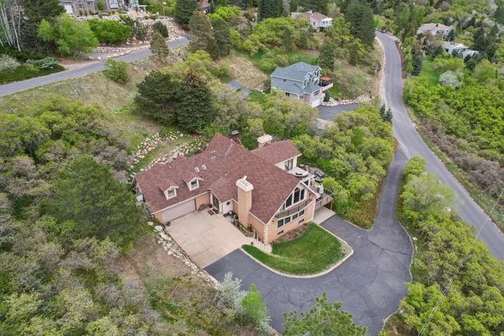 Hillside residence featuring a brown shingle roof, light brick and siding exterior, and multiple gabled dormers