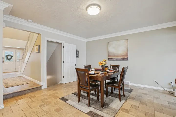 Dining area featuring tile flooring, crown molding, and a built-in light fixture