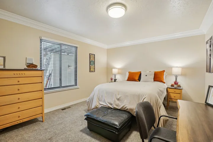 Carpeted room featuring a window with blinds, crown molding, and a flush-mount ceiling light