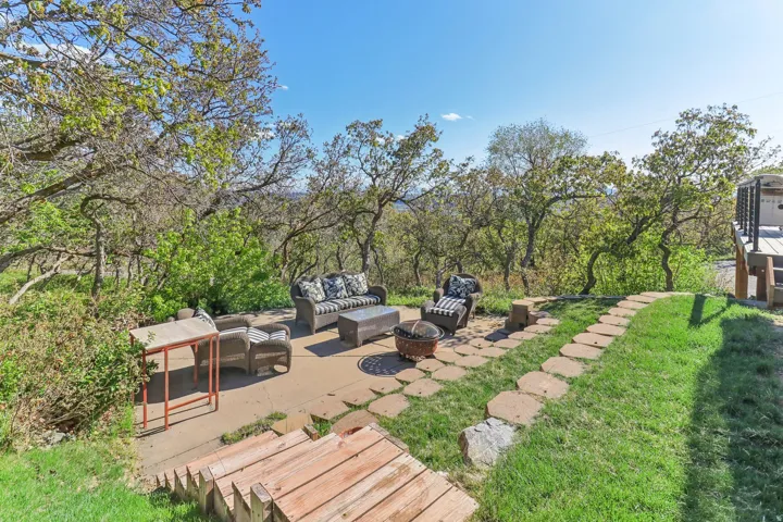 Outdoor patio with a stone paver path, surrounded by mature trees and natural landscaping
