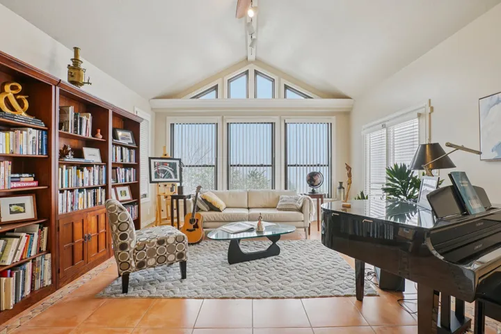 Spacious living area featuring a vaulted ceiling with clerestory windows, tile flooring, and a wall of built-in wood cabinetry