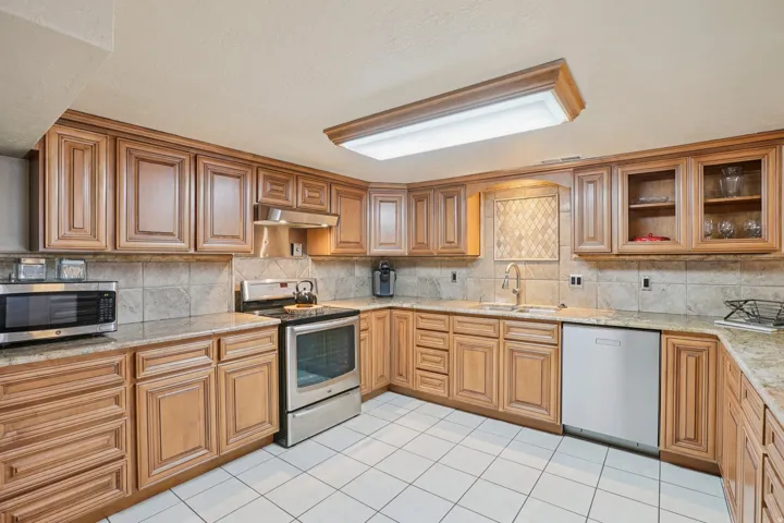 Kitchen with extensive wood-finish cabinetry, light-toned countertops, and a tile backsplash