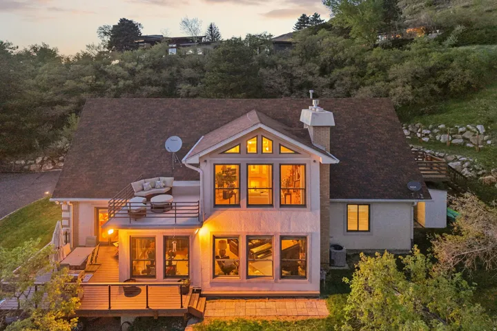 Multi-level residence featuring a prominent gabled roofline, expansive window arrangements, and a lower-level wood deck