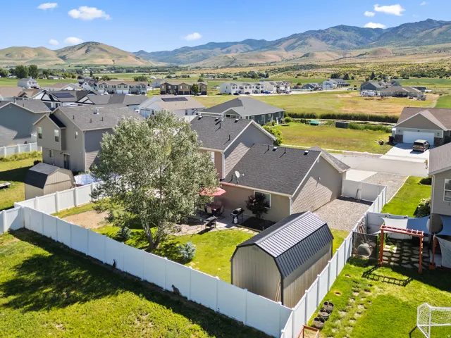 Expansive backyard with a white privacy fence, mature trees, and a storage shed
