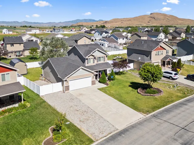 Two-story residence featuring a two-car garage, concrete driveway, and a gravel strip