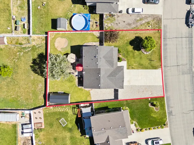 Expansive lot featuring mature landscaping, a paved driveway, and a backyard patio area