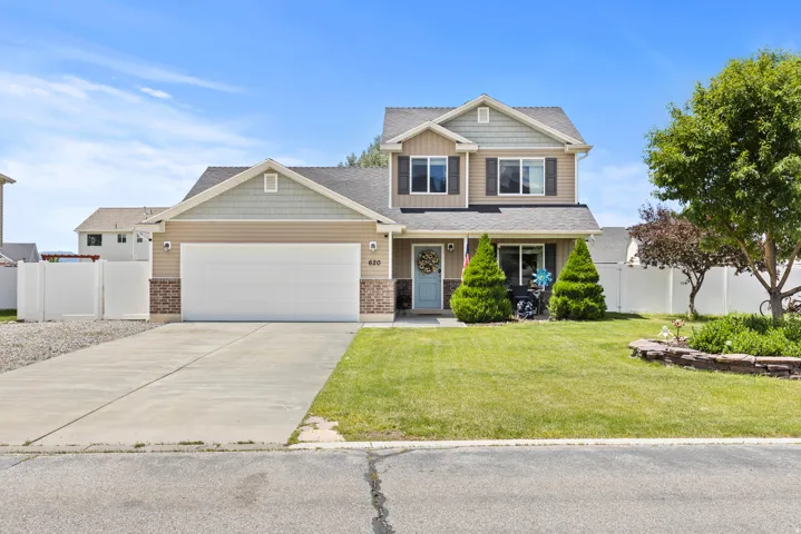 Two-story residence featuring a two-car garage, manicured lawn, and a light blue entry door