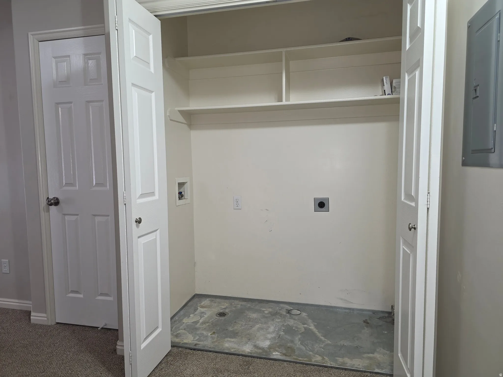 Laundry area featuring bi-fold doors, built-in shelving, concrete flooring, and an electrical panel