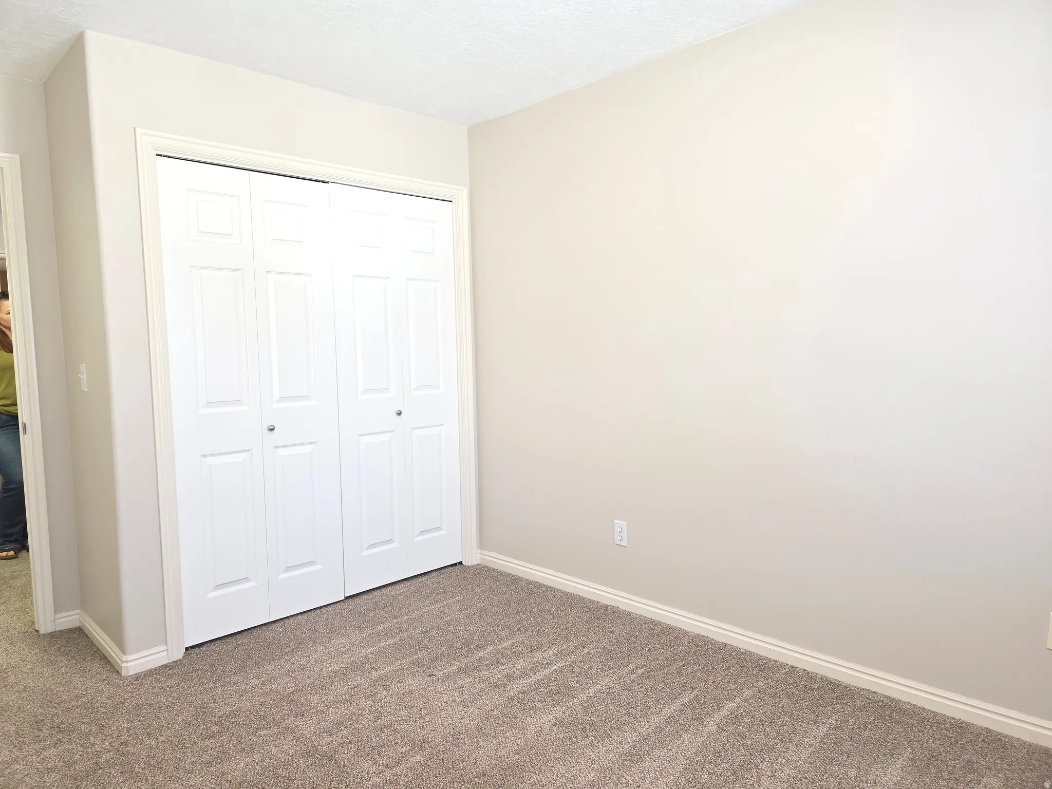 Neutral-toned carpeting and walls complement the white bi-fold closet doors