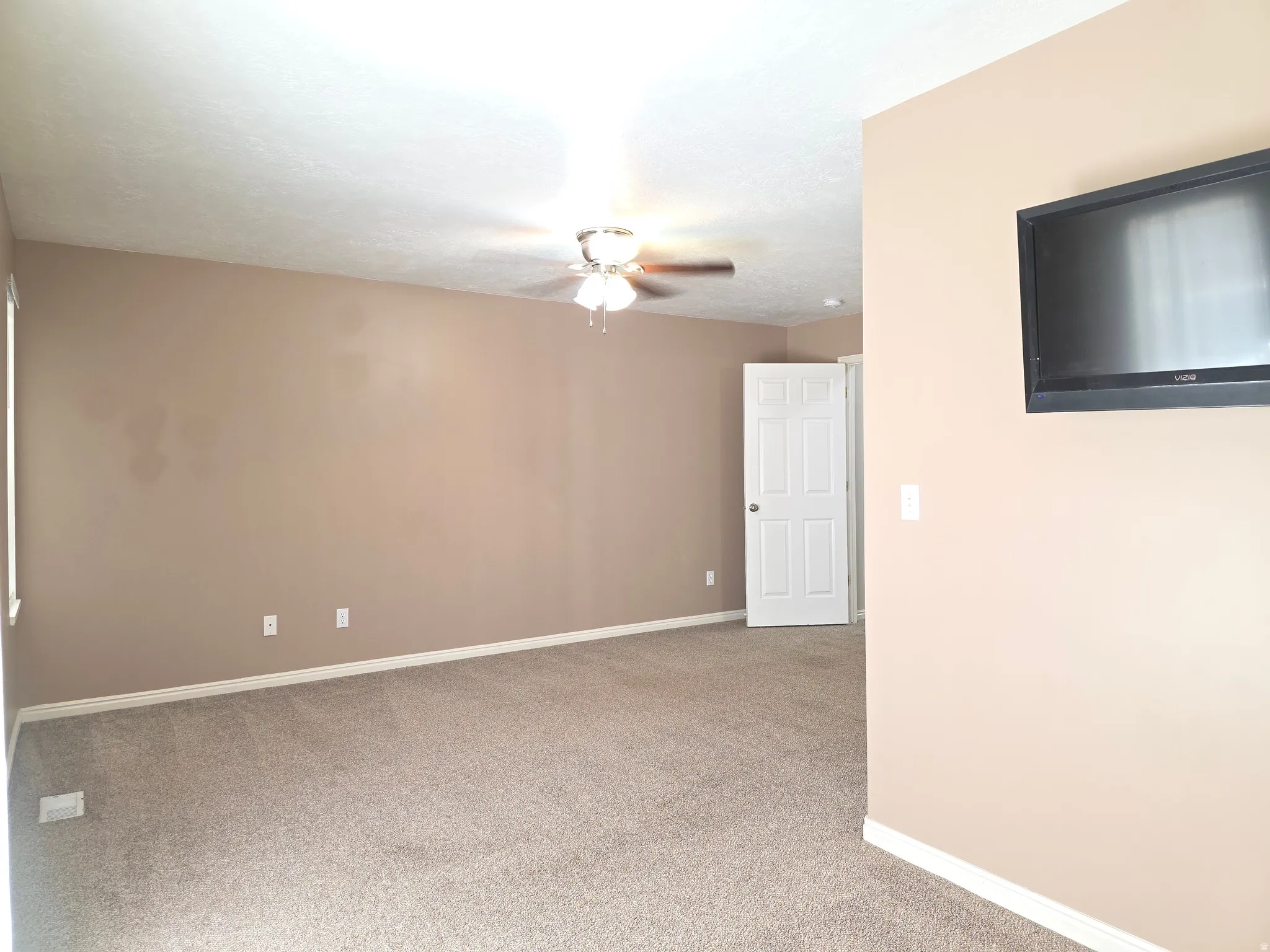 Spacious room featuring neutral carpeting, light beige wall color, and white baseboards